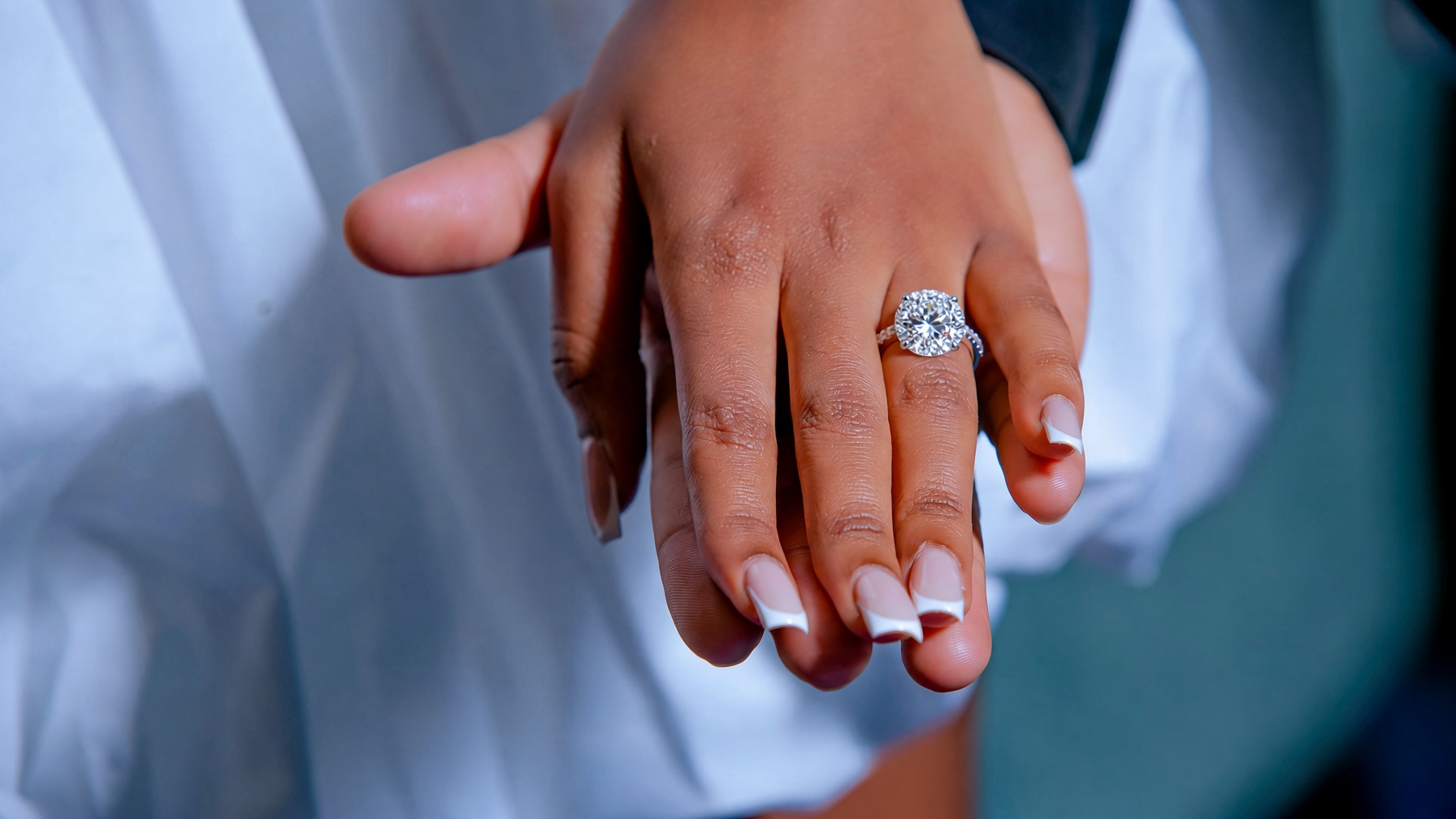 A couple, her hand on his, a diamond on her finger